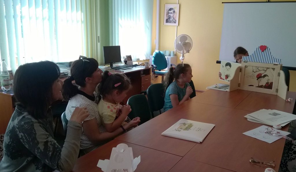 Dzieci bawią się w teatrzyk kamishibai w bibliotece.