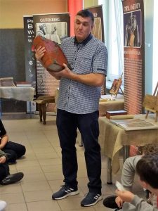 Autor wystawy przemawia do zwiedzającej wystawę młodzieży.