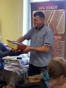 Jarosław Gaudek na tle banera "Jan Wiklif"