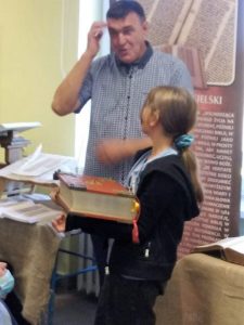 Jarosław Gaudek i dziewczynka trzymająca wielką księgę.