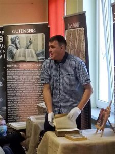 Jarosław Gaudek w białych rękawiczkach prezentuje stary egzemplarz Biblii.