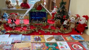 Wystawka książek bożonarodzeniowych w otoczeniu świątecznych dekoracji: szopki, mikołajów, łańcuchów, choinek.