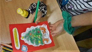 Dłonie dziecka prezentujące wykonaną przez siebie kartką świąteczną.