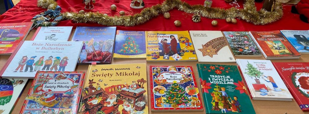 Okładki książek o tematyce bożonarodzeniowej w otoczeniu świątecznych ozdób: złotych łańcuchów, szyszek i orzechów.