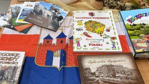 Wokół flagi z herbem Bydgoszczy leżą na stole książki o tym mieście i województwie kujawsko-pomorskim.