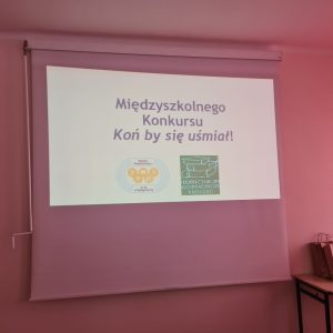 Widok na ekran z logotypami SP nr 31 i PBW w Bydgoszczy oraz napisem Międzyszkolny Konkurs pt. "Koń by się uśmiał".