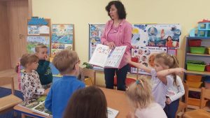 Nauczycielka pokazuje przedszkolakom otwartą książkę.