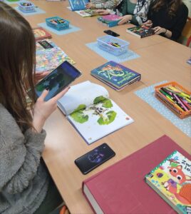 Dziewczyna kieruje tablet na książkę z rozszerzoną rzeczywistością.