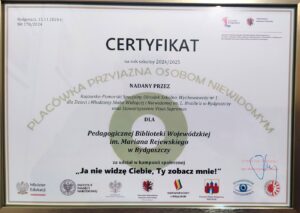 Certyfikat "Placówka Przyjazna Osobom Niewidomym" w złotej ramce.