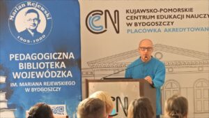 Prelegent na tle banerów PBW w Bydgoszczy i KPCEN.