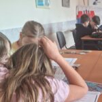 Dzieci przy stolikach z mapkami, kartkami.