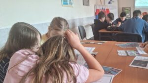 Dzieci przy stolikach z mapkami, kartkami.