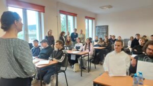 Kobieta zwrócona do sali wypełnionej młodzieżą.