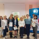 Grupa kobiet pozuje z dyplomami w rękach.