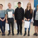 Troje uczniów z dyplomem i torbami prezentowymi pozują do zdjęcia z trzema nauczycielkami.