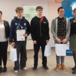 Trzech uczniów z dyplomem i torbami prezentowymi pozują do zdjęcia z trzema nauczycielkami.