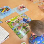 Chłopiec przesuwa pionek na planszy gry.