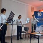 Pięcioro młodych muzyków w białych koszulach z instrumentami dętymi.