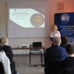 Kobieta przed ekranem z banerem konferencji i roll-upem biblioteki.