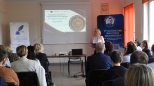 Kobieta przed ekranem z banerem konferencji i roll-upem biblioteki.