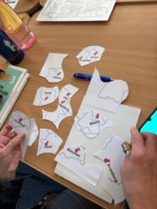 Zbliżenie na dłonie, które układają puzzle z mapą Niemiec.