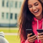 Troje rozbawionych nastolatków ze smartfonami, a obok smutny chłopak siedzi sam.