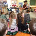 Na zajęciach z małymi dziećmi kobieta prezentuje książkę.