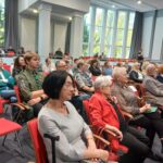 Zdjęcie grupowe ludzi siedzących w sali widowiskowej.