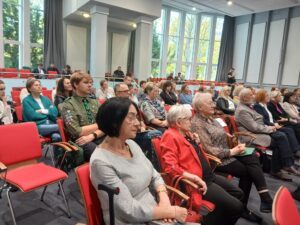 Zdjęcie grupowe ludzi siedzących w sali widowiskowej.