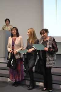 Cztery kobiety. Jedna w tle, 3 pozostałe nagrodzone dyplomami.