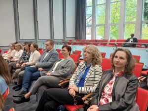 Sześć kobiet i jeden mężczyzna siedzący na krzesłach.
