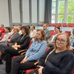 Grupa osób siedząca na krzesłach.