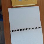 Książka pisana brajlem na stoliku.