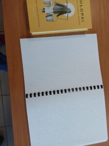 Książka pisana brajlem na stoliku.