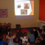 Gromadka dzieci ogląda prezentację na ekranie.