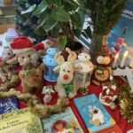 Misie i dekoracje świąteczne pod choinką w otoczeniu książeczek.