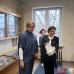 Dwie kobiety w sali muzealnej pozują z grafiką.