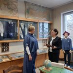 Dwie kobiety w sali muzealnej zwrócone twarzami do siebie.