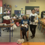 Dwie kobiety pozują do zdjęcia. Ciemnowłosa stoi, blondwłosa siedzi na krześle.