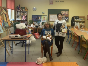 Dwie kobiety pozują do zdjęcia. Ciemnowłosa stoi, blondwłosa siedzi na krześle.