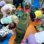 Grupka dzieci pochyla się nad dywanem.