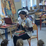 Ciemnowłosa, siedząca kobieta trzyma książkę w ręce.