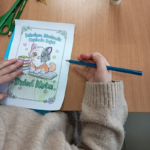 Zdjęcie dziecięcej ręki kolorującej obrazek z kotem.