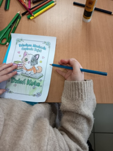 Zdjęcie dziecięcej ręki kolorującej obrazek z kotem.