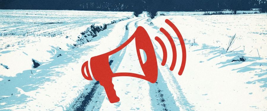 Megafon na tle zimowego pejzażu z zasypaną drogą i polami.