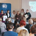 Sala audytoryjna pełna słuchaczy, do zdjęcia pozuje 6 kobiet.