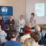 Sala audytoryjna pełna słuchaczy, jako mówcy stoją 4 kobiety.