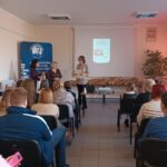 Sala audytoryjna pełna słuchaczy, jako mówcy stoją 3 kobiety.