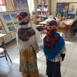 Dwoje dzieci stojących tyłem w strojach ludowych.