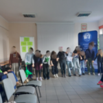 Kilku uczniów stoi na przedzie sali dydaktycznej.